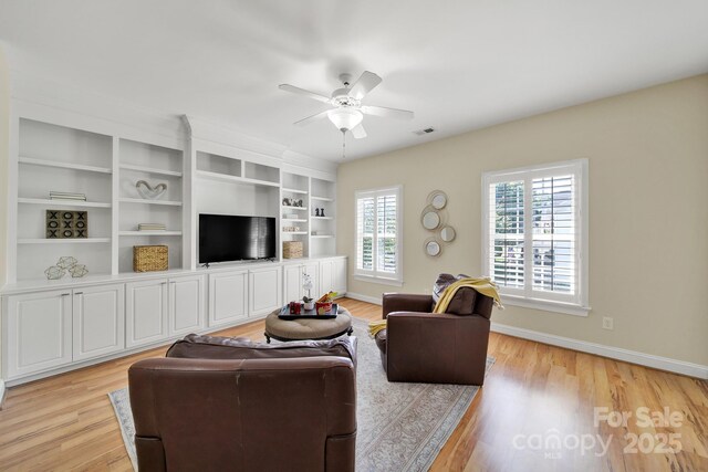 living room featuring a ceiling fan, baseboards, visible vents, and light wood finished floors