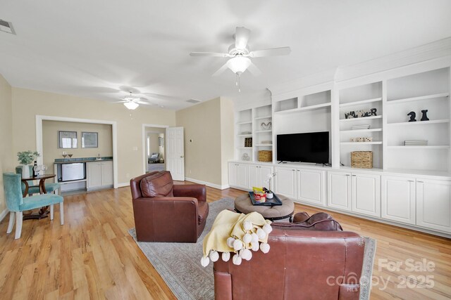 living room featuring baseboards, ceiling fan, and light wood-style flooring