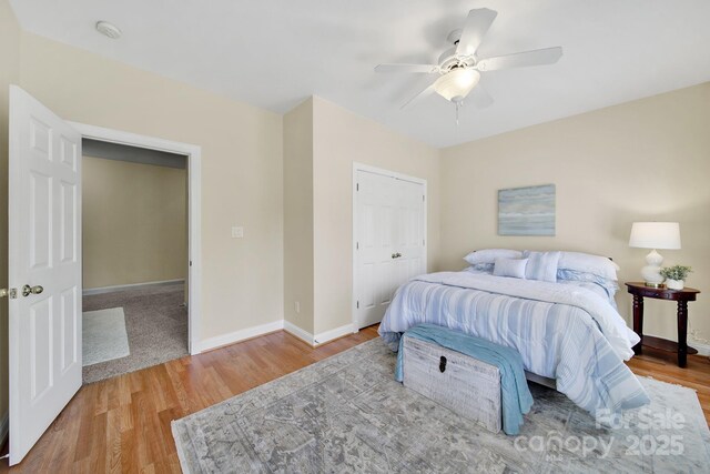 bedroom with a ceiling fan, baseboards, wood finished floors, and a closet