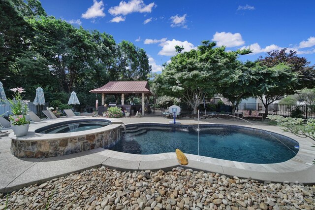 view of swimming pool with fence, a patio, a gazebo, and a pool with connected hot tub