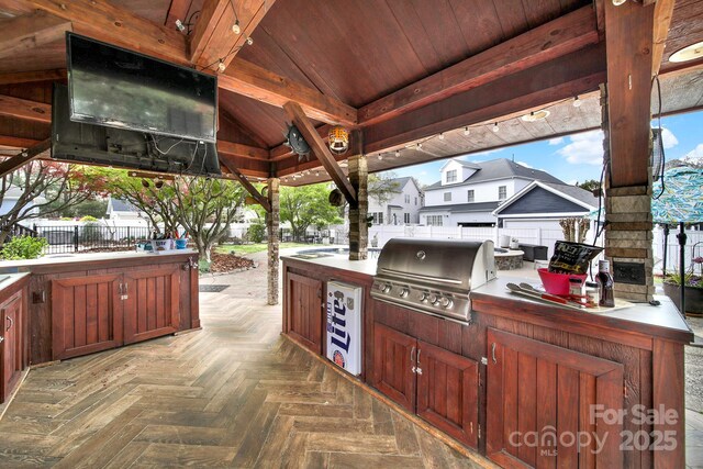 view of patio featuring fence, grilling area, a deck, and an outdoor kitchen