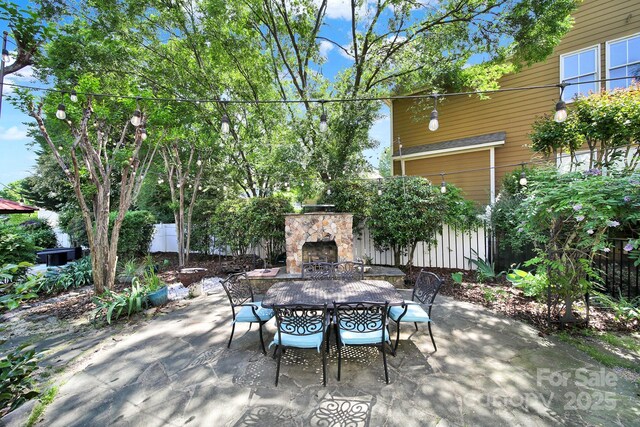 view of patio / terrace with an outdoor stone fireplace, fence, and outdoor dining space