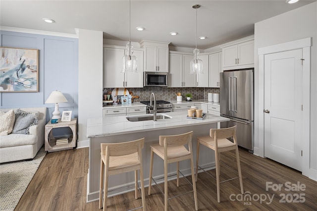 kitchen featuring high quality appliances, tasteful backsplash, white cabinetry, a breakfast bar area, and dark wood-style flooring