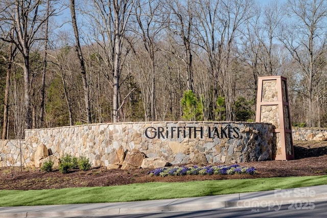 community / neighborhood sign featuring a wooded view