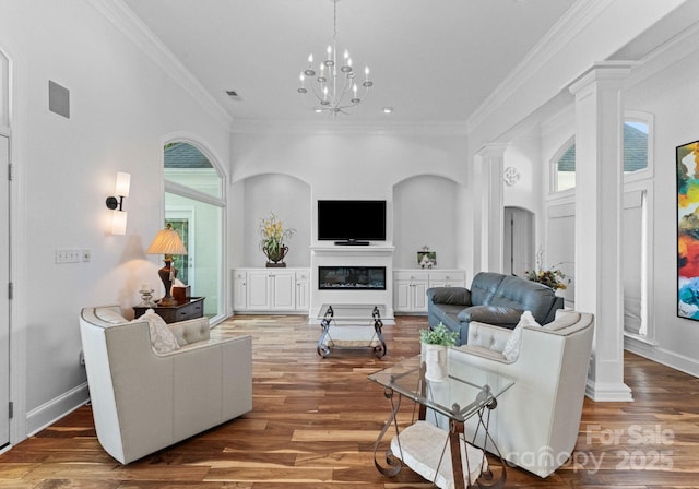 102 Stone Point Ct, Mooresville, NC 28117 - living area with ornate columns, crown molding, wood finished floors, a glass covered fireplace, and a chandelier