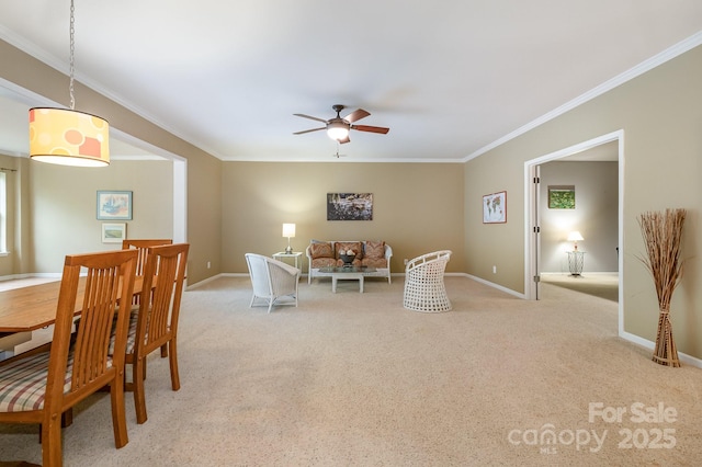 carpeted dining room featuring a ceiling fan, baseboards, and crown molding