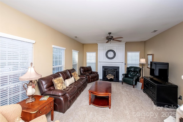 carpeted living room with a fireplace, a ceiling fan, and visible vents