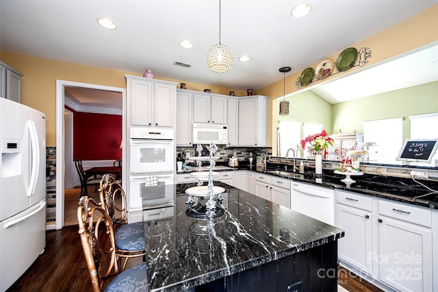 kitchen featuring white appliances, visible vents, a sink, dark wood-type flooring, and decorative light fixtures