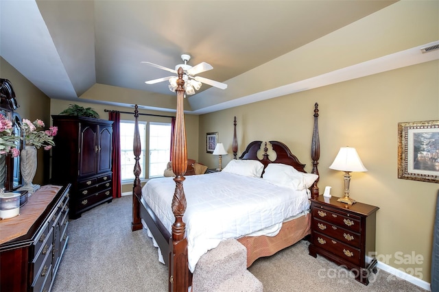 bedroom with light carpet, ceiling fan, baseboards, and a tray ceiling