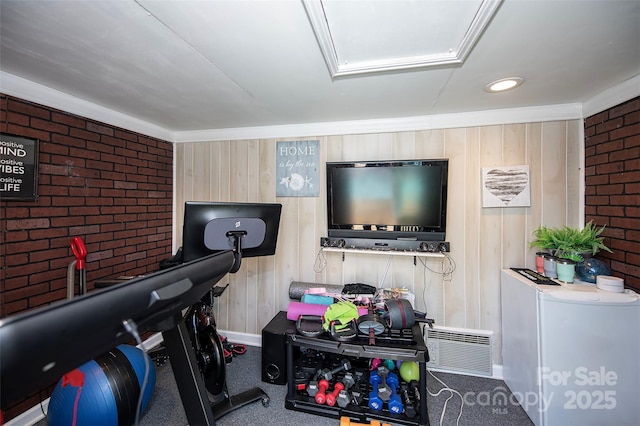 exercise room with attic access, visible vents, and brick wall