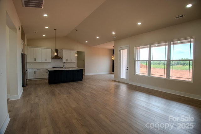 1370 Coppergate Dr, Salisbury, NC 28147 - kitchen featuring wall chimney range hood, open floor plan, freestanding refrigerator, an island with sink, and wood finished floors