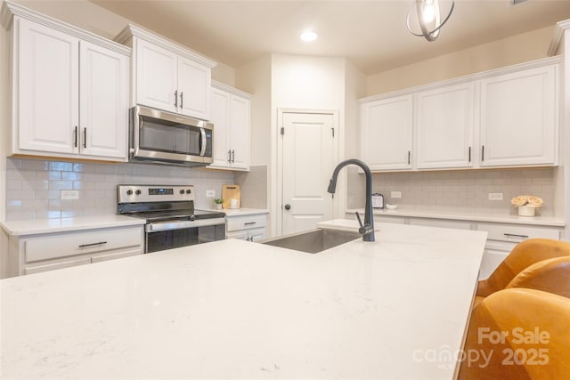 13024 Suncreek Ter, Charlotte, NC 28214 - kitchen featuring decorative backsplash, appliances with stainless steel finishes, a sink, and white cabinetry