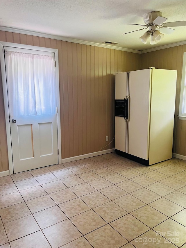 3232 Wilson Heights Dr, Hildebran, NC 28637 - kitchen featuring white fridge with ice dispenser, plenty of natural light, ornamental molding, light tile patterned floors, and wooden walls