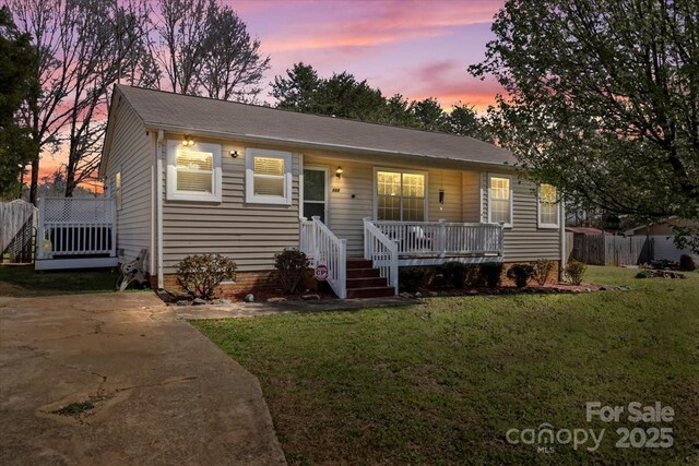 view of front facade featuring covered porch, a front lawn, and fence