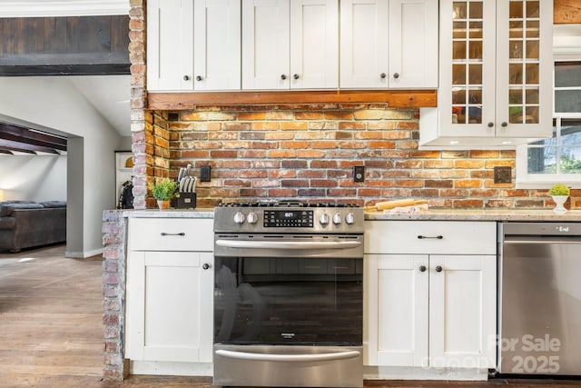 203 Davis Mountain Rd, Laurel Park, NC 28739 - kitchen featuring appliances with stainless steel finishes, white cabinetry, light wood finished floors, light stone countertops, and vaulted ceiling