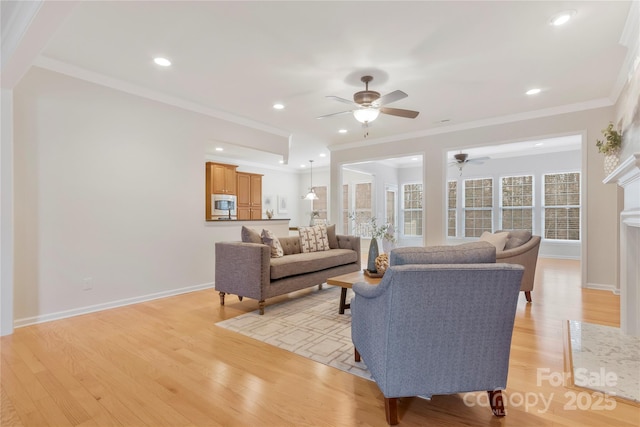 living room with light wood-style flooring, ornamental molding, baseboards, and a ceiling fan