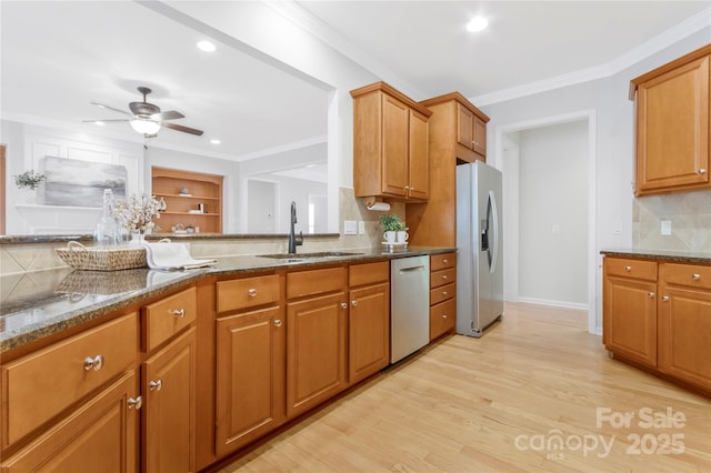 kitchen with tasteful backsplash, light wood-type flooring, dark stone countertops, stainless steel appliances, and a sink