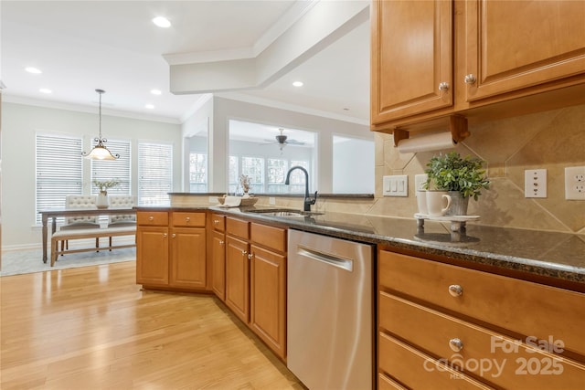 kitchen with a sink, light wood-type flooring, dark stone counters, and dishwasher