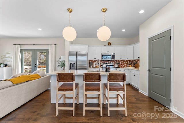 kitchen featuring white cabinetry, stainless steel appliances, french doors, light countertops, and decorative backsplash