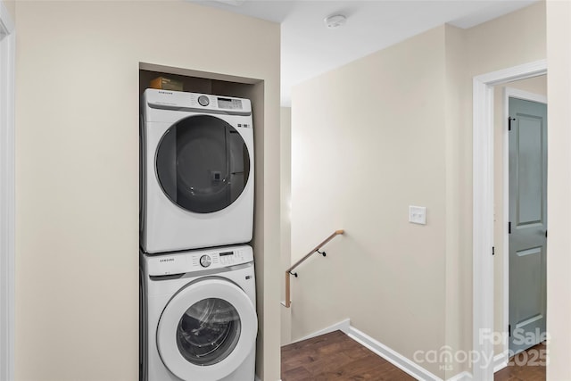 laundry area featuring baseboards, dark wood finished floors, laundry area, and stacked washer / dryer