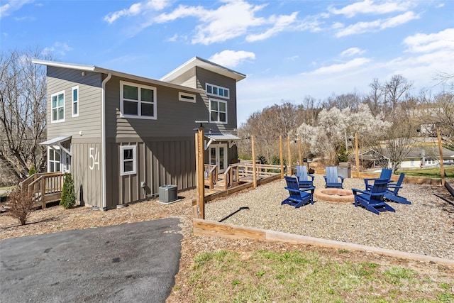 exterior space with a wooden deck, cooling unit, board and batten siding, and an outdoor fire pit