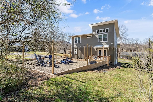 rear view of property featuring a lawn, a pergola, and a deck