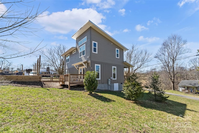 view of side of home featuring a lawn, board and batten siding, and a deck
