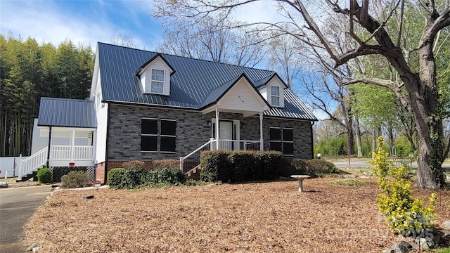 view of front facade with a porch, stone siding, and metal roof