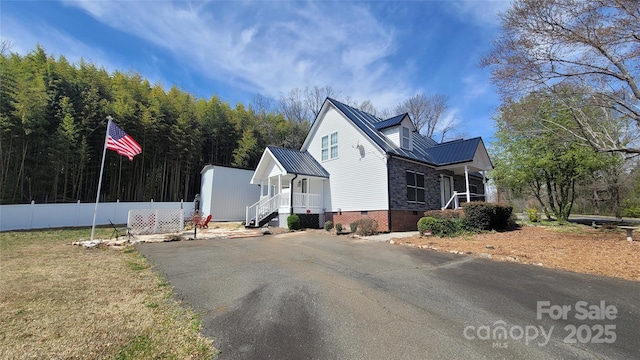 view of home's exterior featuring aphalt driveway, crawl space, fence, and metal roof