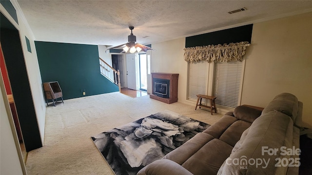 carpeted living area featuring visible vents, a textured ceiling, ceiling fan, and stairway