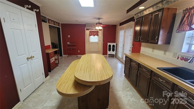 kitchen featuring light countertops, dark brown cabinetry, a wealth of natural light, and a sink