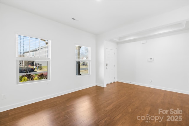 unfurnished room with visible vents, baseboards, and wood finished floors