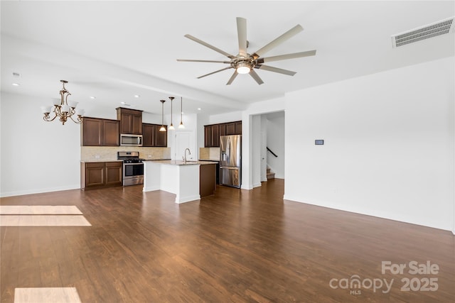 kitchen with visible vents, ceiling fan with notable chandelier, a sink, open floor plan, and stainless steel appliances