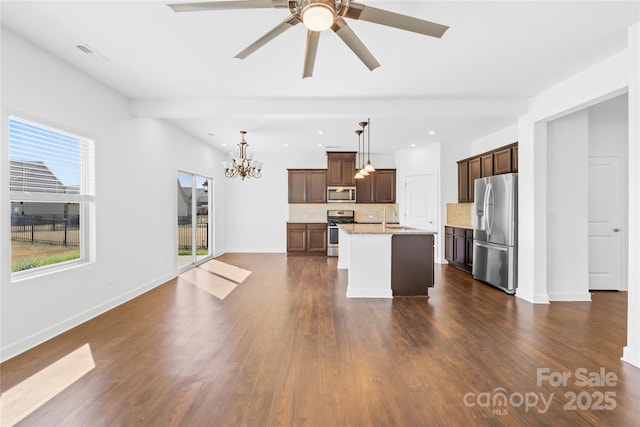 kitchen featuring dark wood finished floors, a sink, appliances with stainless steel finishes, ceiling fan with notable chandelier, and backsplash