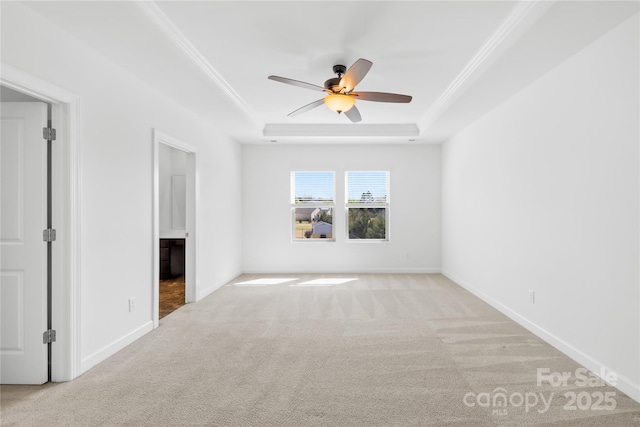 carpeted spare room with baseboards, a raised ceiling, ceiling fan, and ornamental molding