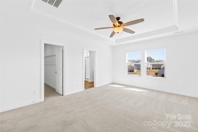 unfurnished bedroom with visible vents, a tray ceiling, carpet floors, baseboards, and a spacious closet