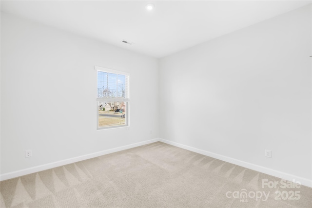 spare room featuring visible vents, light colored carpet, and baseboards