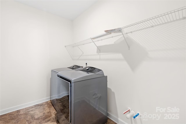 laundry area with laundry area, washing machine and dryer, and baseboards
