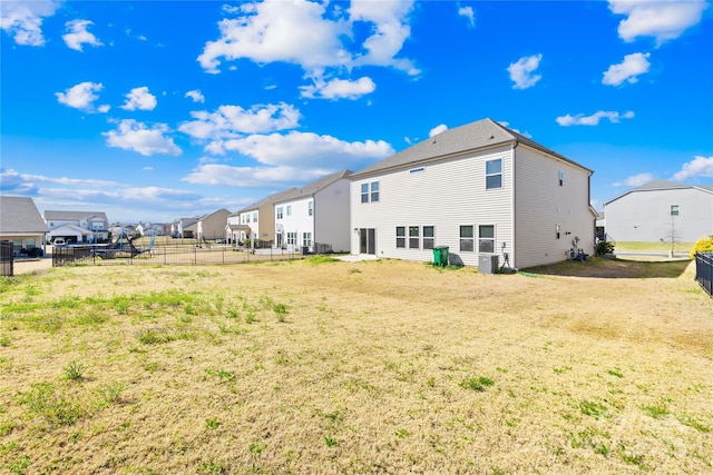 back of property featuring a residential view, cooling unit, a yard, and fence