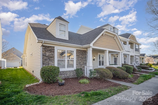 view of front of house with a front lawn, stone siding, and a shingled roof