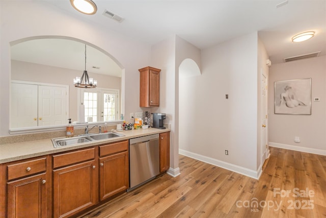 kitchen featuring brown cabinetry, visible vents, arched walkways, a sink, and stainless steel dishwasher