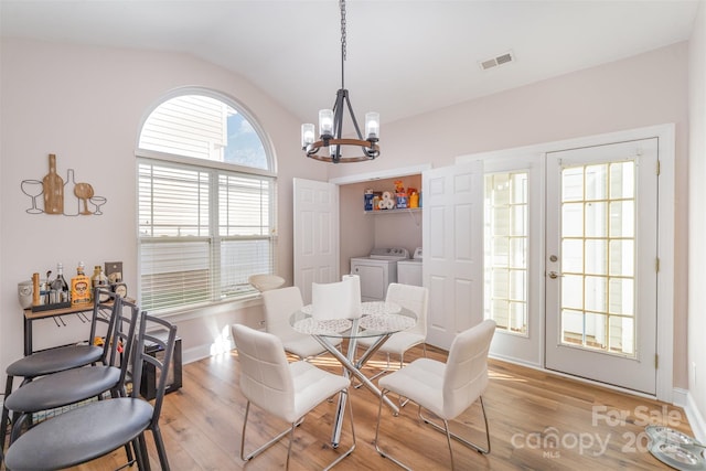dining room with visible vents, a notable chandelier, light wood-style floors, separate washer and dryer, and lofted ceiling