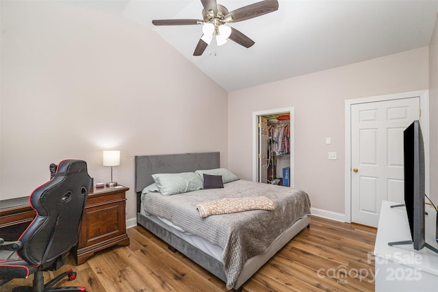 bedroom featuring a spacious closet, baseboards, lofted ceiling, light wood-style floors, and a closet