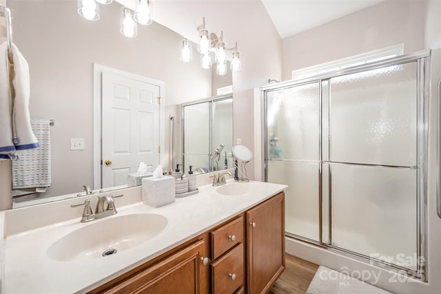 bathroom featuring a shower stall, wood finished floors, double vanity, and a sink