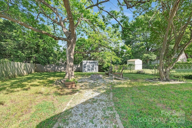 view of yard with an outdoor structure, a fenced backyard, and a shed