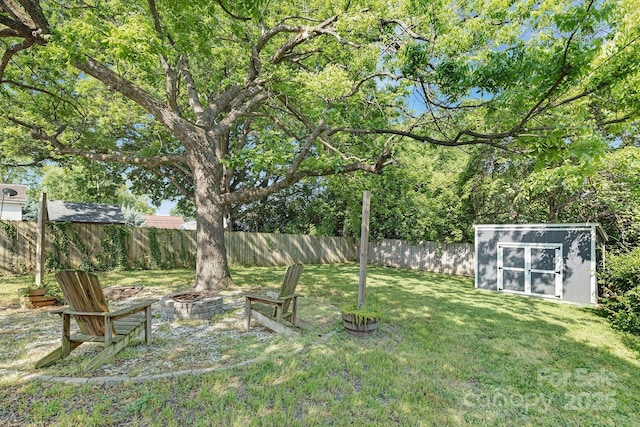 view of yard with a storage unit, a fenced backyard, an outdoor fire pit, and an outbuilding