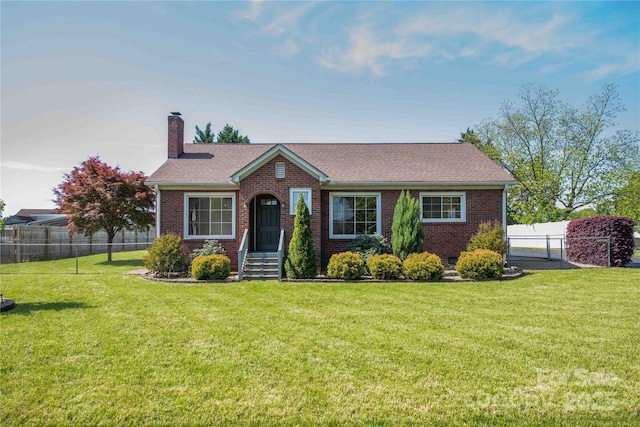 view of front of home with brick siding, a chimney, a front lawn, and fence