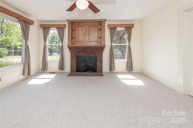 unfurnished living room with a brick fireplace, carpet flooring, and ceiling fan