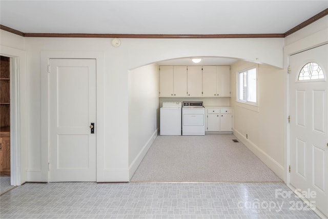 laundry area featuring washer and clothes dryer, arched walkways, baseboards, cabinet space, and crown molding