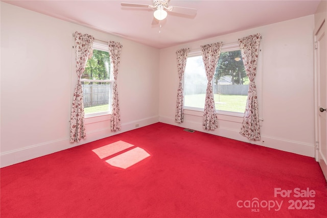 carpeted empty room with visible vents, baseboards, and ceiling fan